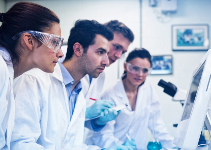 Side view of serious researchers looking at computer screen in t Team-vacuum-packaging